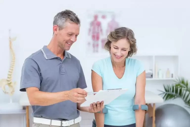 A chiropractor talking with a patient during an exam