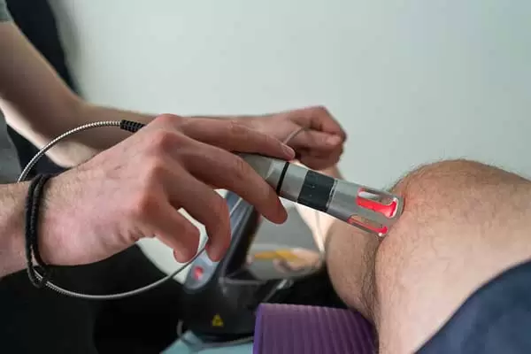 A cold laser held over a patient’s knee