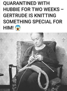 Elderly woman sitting in chair knitting a long item with knitting needles